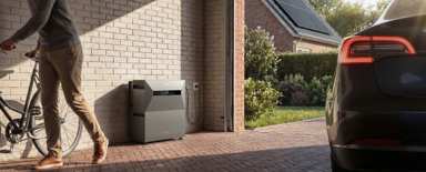 Solarbank Max AC bij de garage, naast zonnepanelen en een elektrische auto
